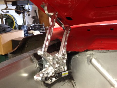 1964 Ford Fairlane - Custom aluminum hood hinges are installed in the trunk area of a red vehicle, with workshop equipment visible.