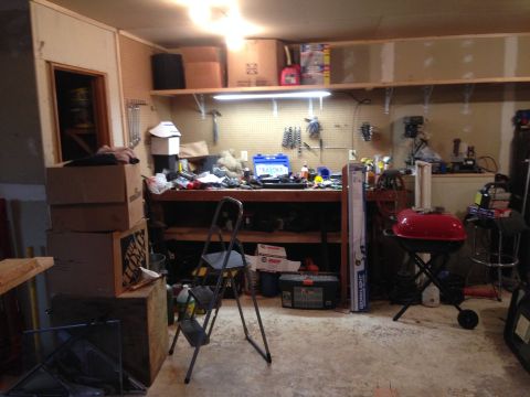 1964 Ford Fairlane - A cluttered garage scene shows a workbench filled with tools, storage boxes, and a red barbecue grill.