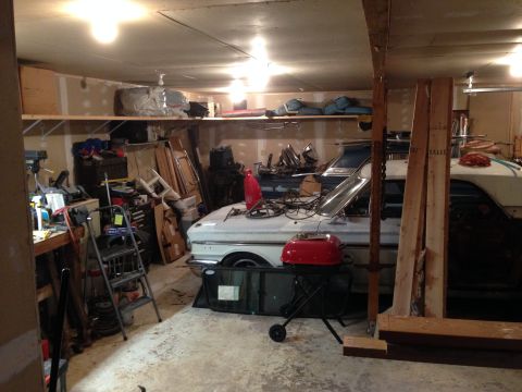 1964 Ford Fairlane - A 1964 Ford Fairlane is parked in a cluttered garage, surrounded by tools and automotive parts.