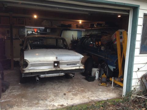 1964 Ford Fairlane - A 1964 Ford Fairlane sits in a garage, partially disassembled, with another vehicle visible behind it.