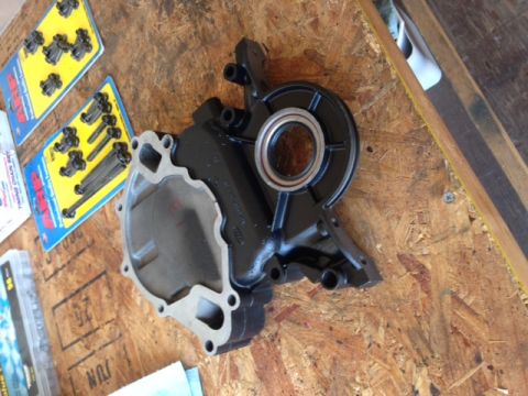 1996 Ford Bronco - An engine water pump and timing chain bolts are laid out on a wooden surface.