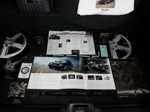 2003 Mercury Marauder - Promotional materials for the 2003 Mercury Marauder, including brochures, wheels, and a t-shirt, are displayed in a trunk.