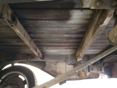 1964 Ford Ranchero - The undercarriage of a vehicle displays significant rust on its structural components and bed.