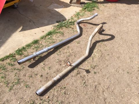 1964 Ford Ranchero - Two exhaust pipes are laid out on the ground, one appearing newer than the other.
