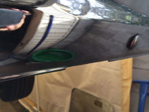 1964 Ford Ranchero - A close-up view of a vehicle's undercarriage reveals a green cap and a chrome fastener.