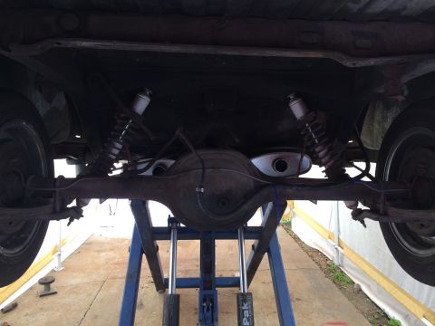 1964 Ford Ranchero - The rear axle and exhaust system of a vehicle are visible from below, supported by a lift.