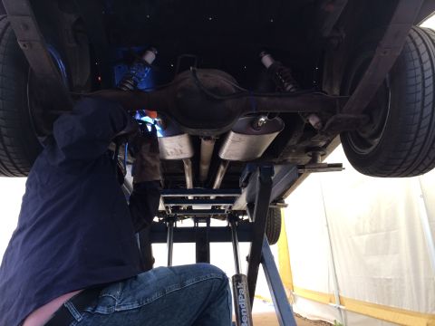 1964 Ford Ranchero - Mechanic welding the exhaust system of a vehicle that is raised on a lift.
