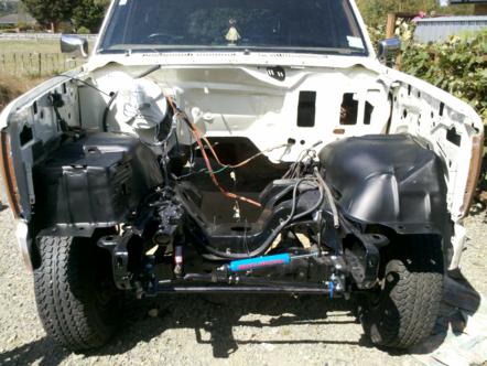 1982 Ford Bronco - The engine bay of a white SUV is exposed, with the engine and some components removed.