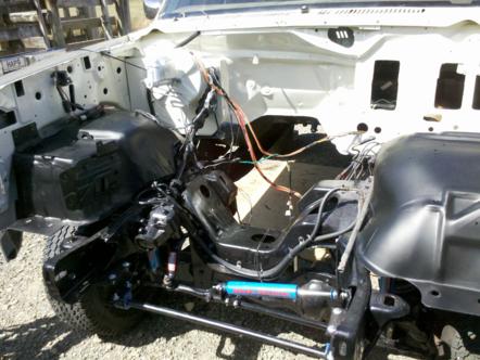 1982 Ford Bronco - The engine bay of a white Ford Bronco shows exposed wiring and frame components.