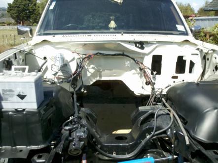 1982 Ford Bronco - The engine bay of a 1982 Ford Bronco shows the battery and exposed wiring, indicating it is ready for engine work.