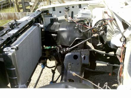 1982 Ford Bronco - The engine bay of a white vehicle is shown, with the radiator and extensive wiring exposed.