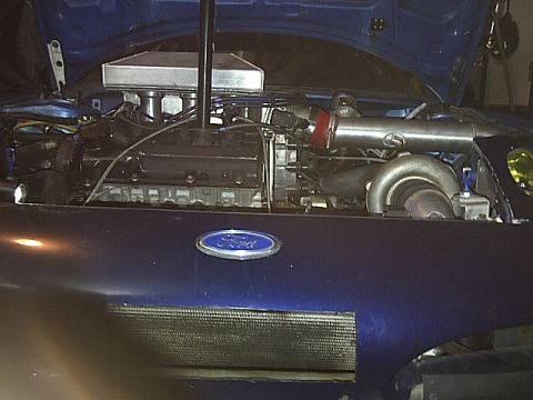 1995 Ford Probe - The engine bay of a blue car is shown with a Ford emblem on the hood and visible engine components.