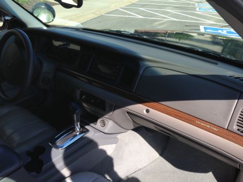 2007 Ford Crown Victoria - The interior of a Crown Victoria is shown, wood trim on the dashboard and a center console with a gear shifter.