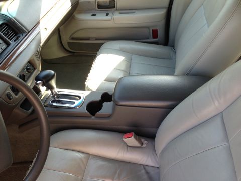 2007 Ford Crown Victoria - The interior of a car features light gray leather seats and a center console with a gear shifter and cup holders.