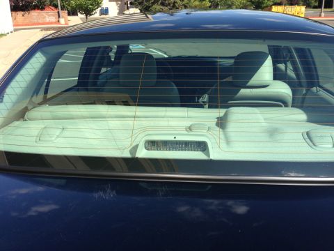 2007 Ford Crown Victoria - The rear window of a dark sedan shows the interior headrests and a third brake light.
