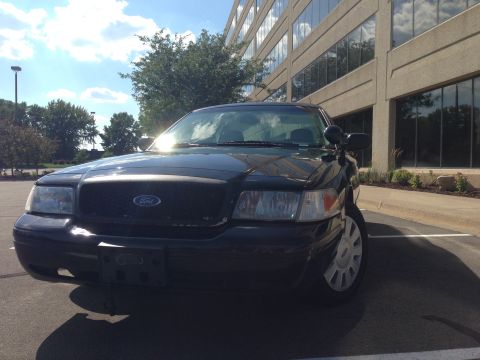 2007 Ford Crown Victoria - Front view of a black 2007 Ford Crown Victoria parked in front of a modern office building.