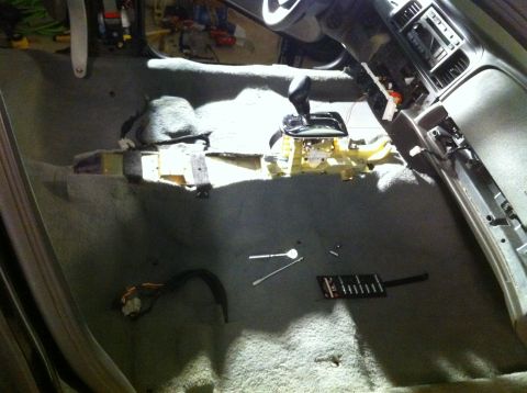 2007 Ford Crown Victoria - The interior of a car is shown with the center console disassembled, revealing the gear shifter and exposed wiring.