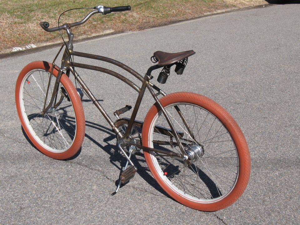 Brown bicycle with orange tires and a leather seat, parked on asphalt