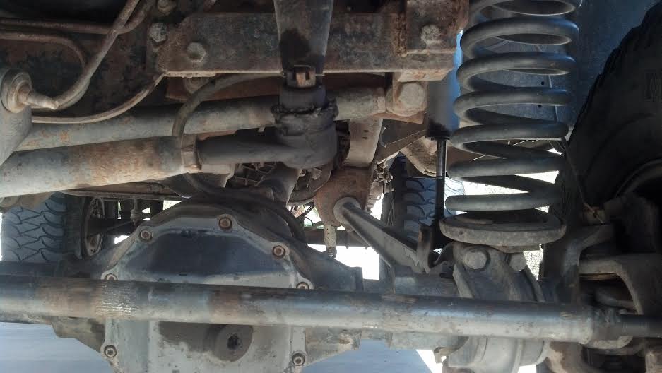 Undercarriage view of a 4x4 with a large differential, coil spring suspension, and steering linkage