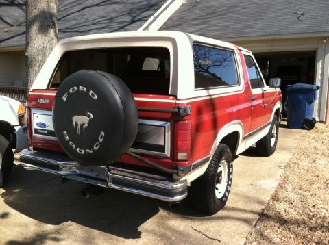 1986 Ford Bronco - Rear view of a red and white Ford Bronco, showing its spare tire and two-tone paint scheme.