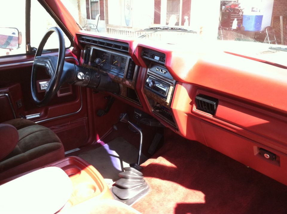 1986 Ford Bronco interior with red dashboard, wood trim, and floor shifter