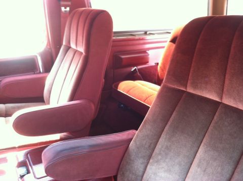 1986 Ford Bronco - Interior view of maroon velour captain's chairs and a rear-facing jump seat.