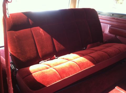 1986 Ford Bronco - Interior view of a red velour rear bench seat, likely from an older SUV or truck.