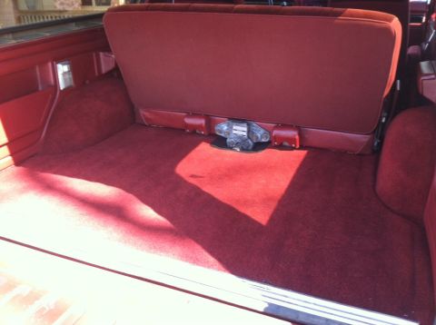 1986 Ford Bronco - The spacious, carpeted cargo area of a 1986 Ford Bronco, a folded rear seat and a visible latch mechanism.
