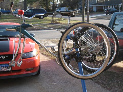 1994 Ford Bronco - An orange Ford Mustang is parked next to a bicycle that is mounted on a repair stand.