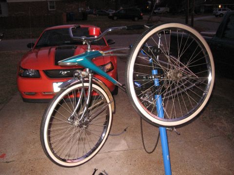 1994 Ford Bronco - A vintage bicycle is being worked on in front of a red Ford Mustang.