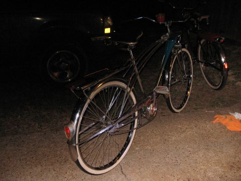 1994 Ford Bronco - Two vintage bicycles with chrome accents and whitewall tires are parked outdoors at night.