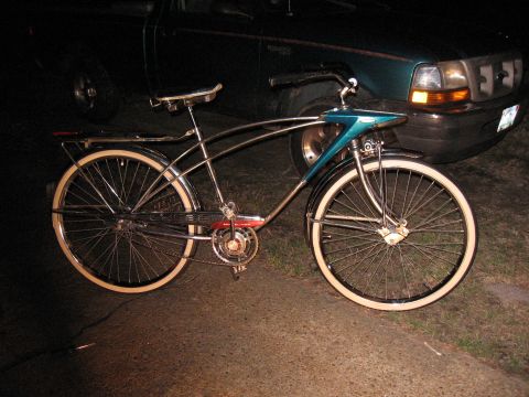 1994 Ford Bronco - A vintage bicycle with chrome accents and whitewall tires is parked in front of a dark-colored pickup truck at night.