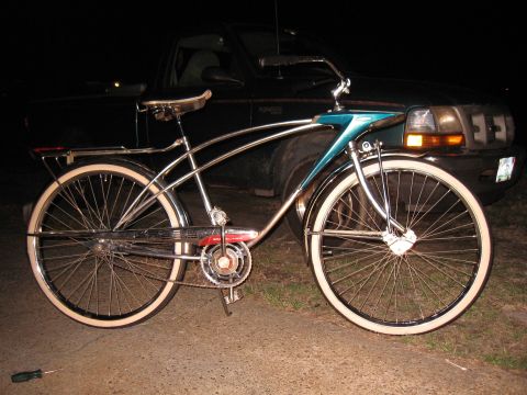1994 Ford Bronco - A vintage bicycle with chrome accents and white-wall tires is parked in front of a dark truck at night.
