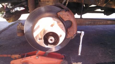 1979 Ford Bronco - A socket wrench is used on the brake caliper of a vehicle, with the rotor and suspension visible.