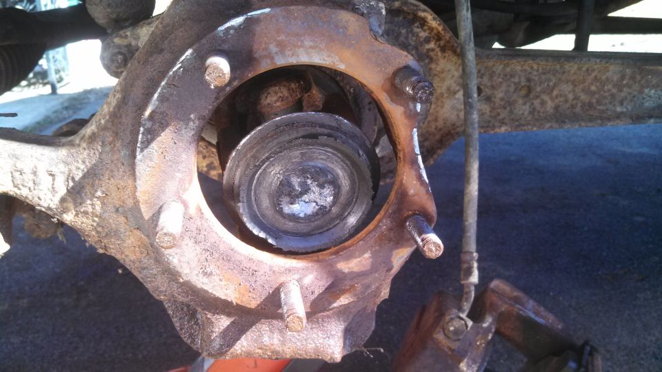 Close-up of a heavily rusted wheel hub assembly with visible bolts and internal components