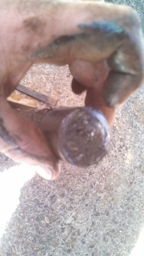 1979 Ford Bronco - A dirty metal part is held in a hand, with a tool in the background.