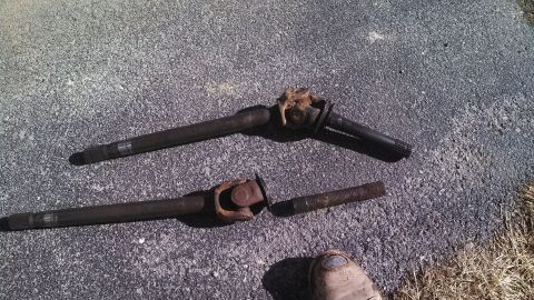 1979 Ford Bronco - Two driveshafts and a broken driveshaft piece are visible on an asphalt surface.
