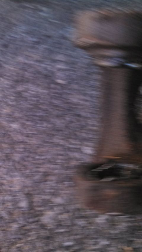 1979 Ford Bronco - Close-up of a rusted metal part resting on a gravel surface.