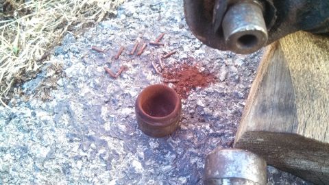 1979 Ford Bronco - Close-up of brake caliper components and debris, with a small container and rust on the ground.