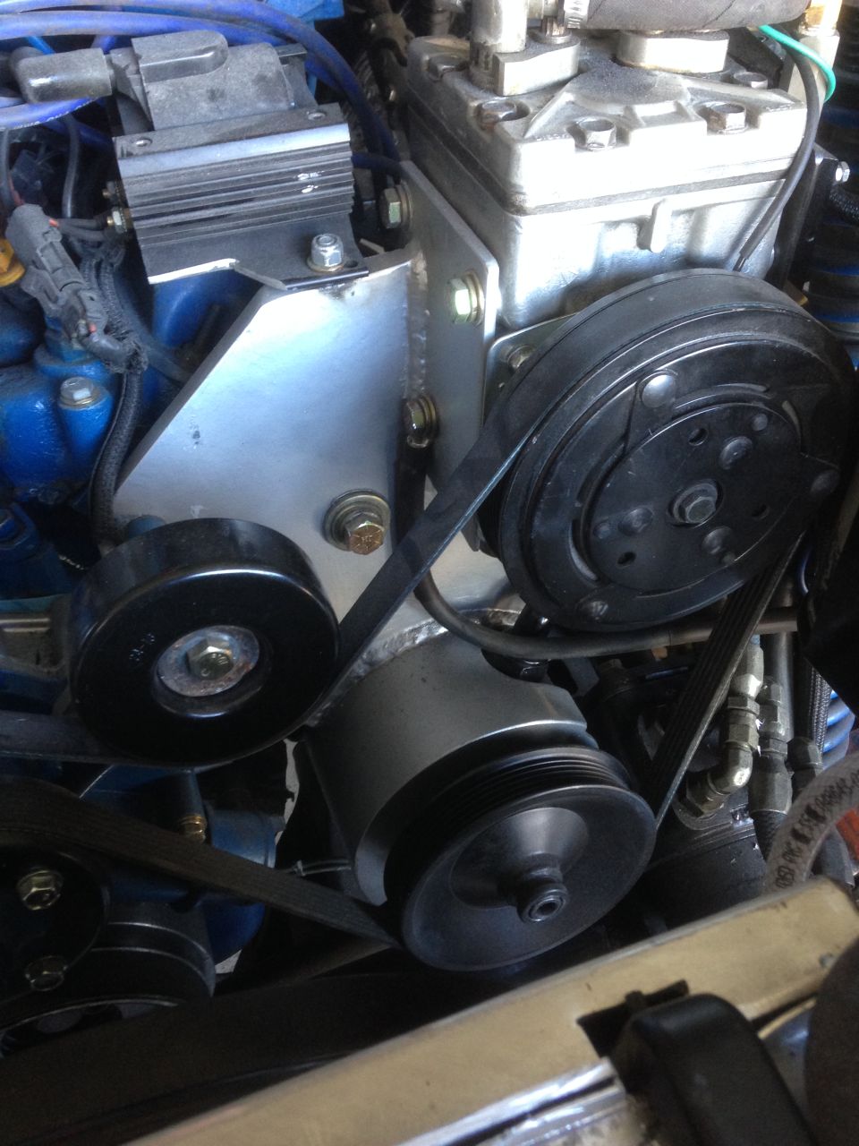 Close-up of engine bay showing AC compressor, belts, and pulleys