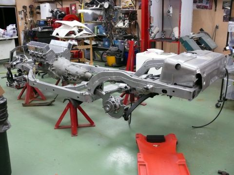 Car chassis on stands with engine and transmission installed, in a workshop