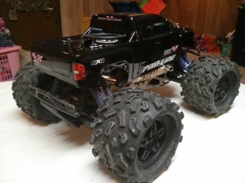 1986 Ford Bronco - A black remote control monster truck with oversized tires sits on a flat surface.