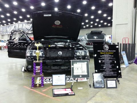2003 Mercury Marauder - A black 2003 Mercury Marauder is displayed with its hood and doors open, alongside trophies and a detailed information board.