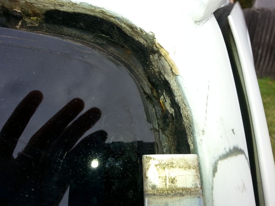 Close-up of a corroded window seal with visible rust and debris