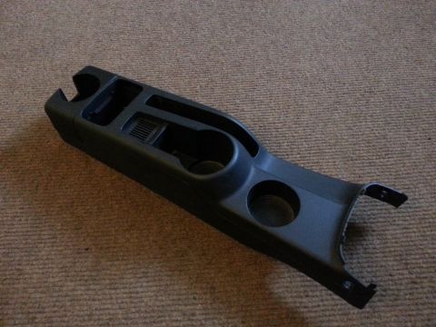 2002 Volkswagen Jetta - A black plastic center console part, cup holders and storage, is shown against a carpeted background.