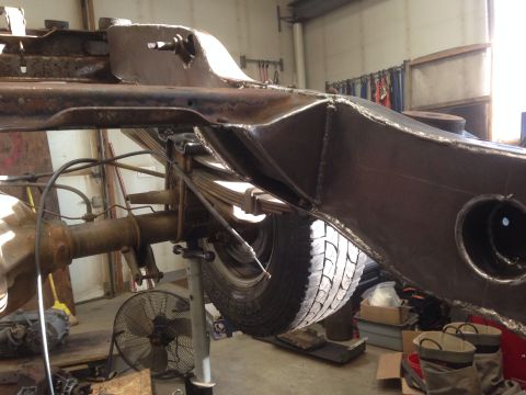1993 Ford Bronco - The underside of a vehicle is shown, focusing on the frame and suspension components in a workshop setting.