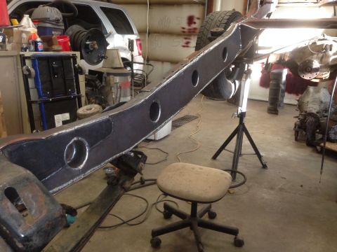1993 Ford Bronco - A vehicle frame is being worked on in a garage, with a silver SUV visible in the background.