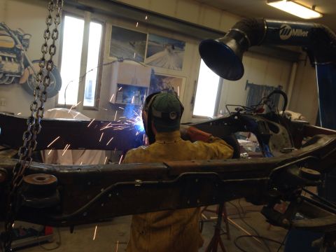 1993 Ford Bronco - A welder works on a vehicle frame in a shop, with a Miller ventilation system above.