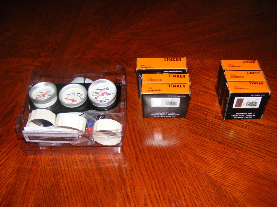 Gauge set in plastic packaging next to three Timken boxes on a wooden surface