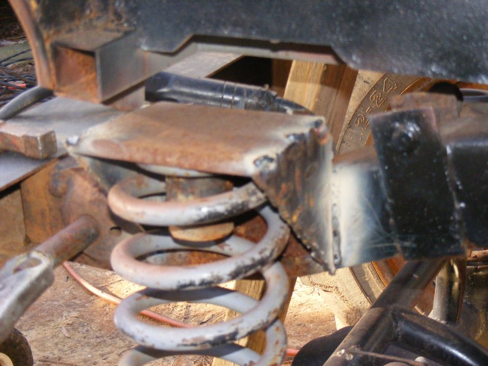 Close-up of a rusty suspension coil spring attached to a metal bracket